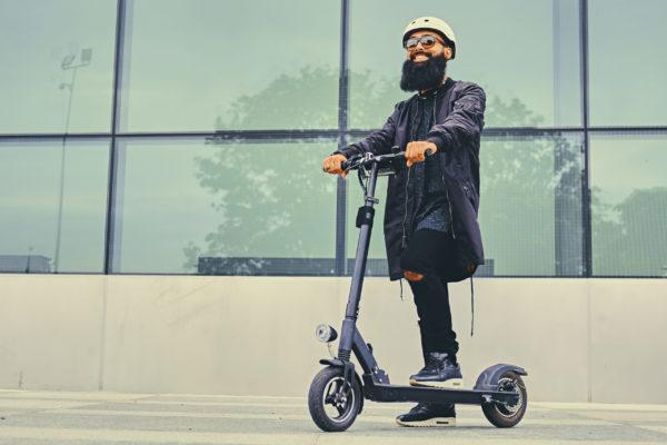A man posing on electric scooter.