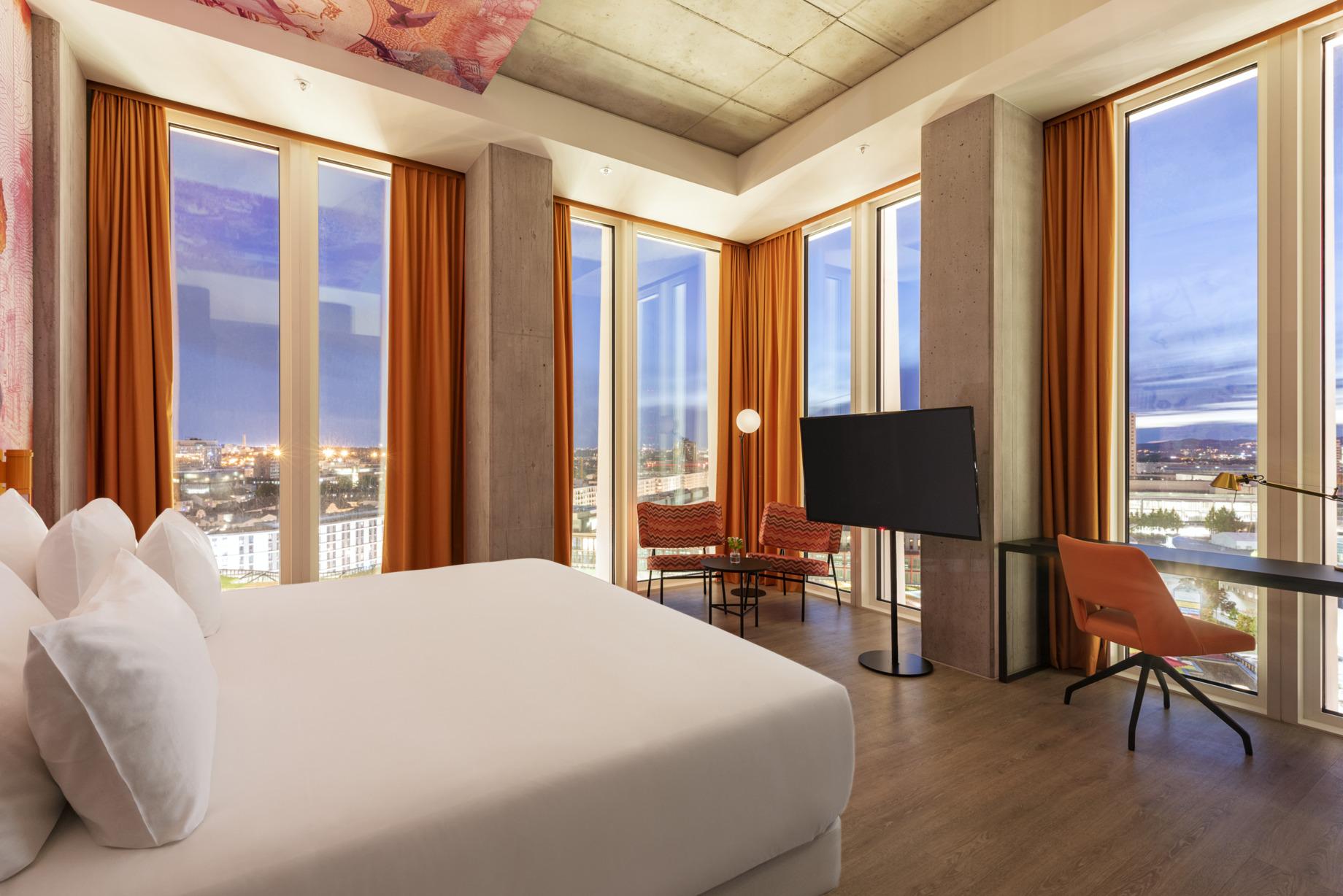 nhow_Frankfurt_Room_suite_curtains_open_king_size_bed_office_chair_armchairs_table_fl